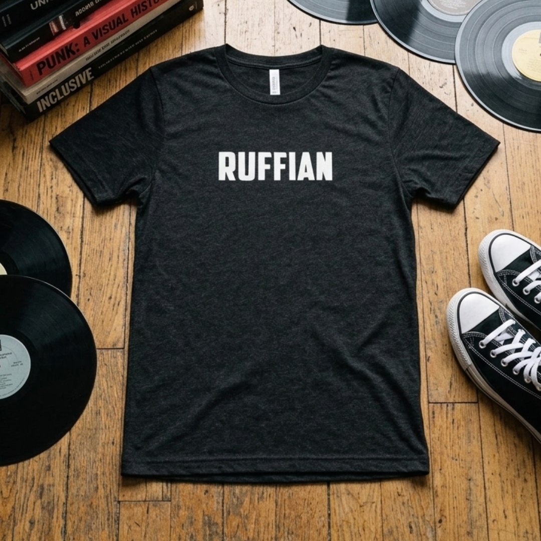 Black Ruffian t-shirt flat lay on wood floor with vinyl records, punk books, and Chuck Taylor sneakers